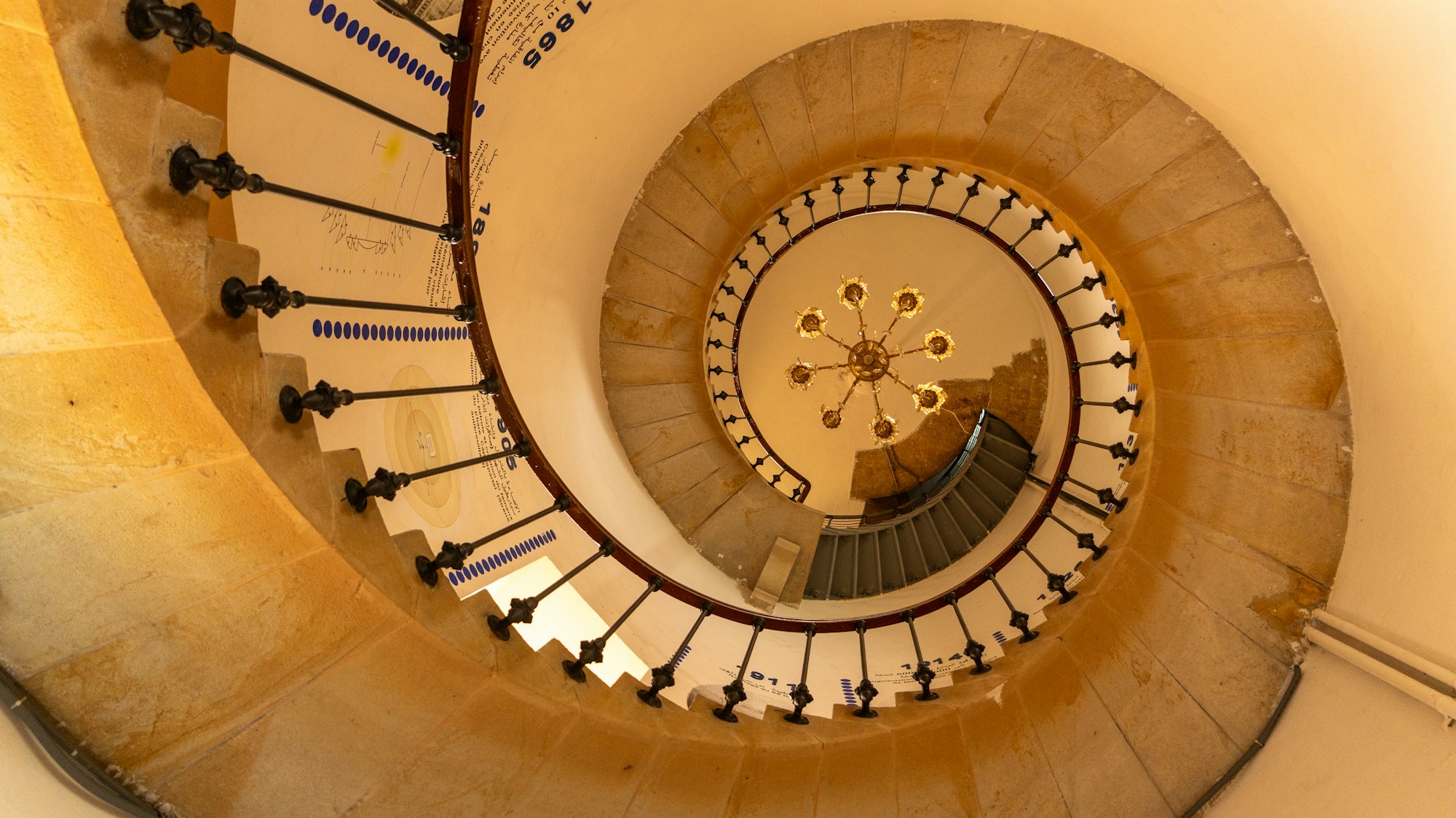 Spiral staircase with warm chandelier inside a designed residence